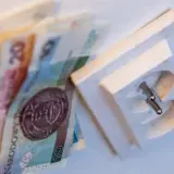 Pieniądze leżą obok gniazdka elektrycznego, symbolizując wysoki rachunek za prąd.