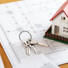 Klucze do domu na planach architektonicznych, symbolizujące zakup nieruchomości i związany z nim podatek PCC.