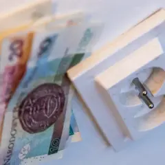 Pieniądze leżą obok gniazdka elektrycznego, symbolizując wysoki rachunek za prąd.