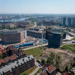 Widok z lotu ptaka na miasto z nowymi budynkami w budowie i portem w tle.