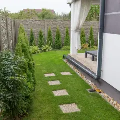 System odprowadzania wody z rynien na trawnik, z rurą spustową skierowaną w stronę ogrodu.