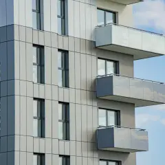 Nowoczesny budynek z balkonami, idealny na rynek wtórny. Jasne panele elewacyjne i duże okna.