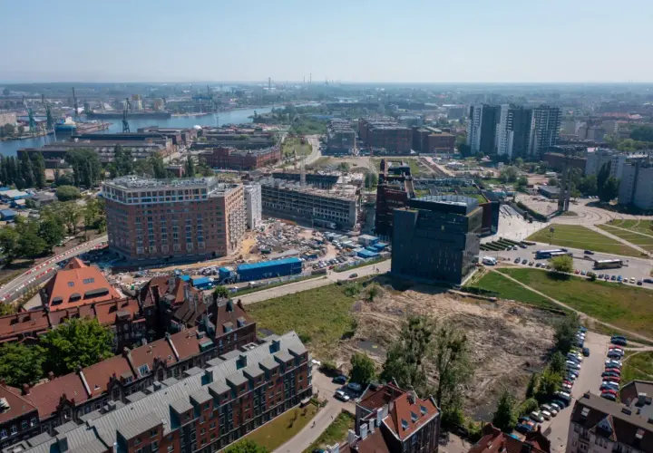 Widok z lotu ptaka na miasto z nowymi budynkami w budowie i portem w tle.