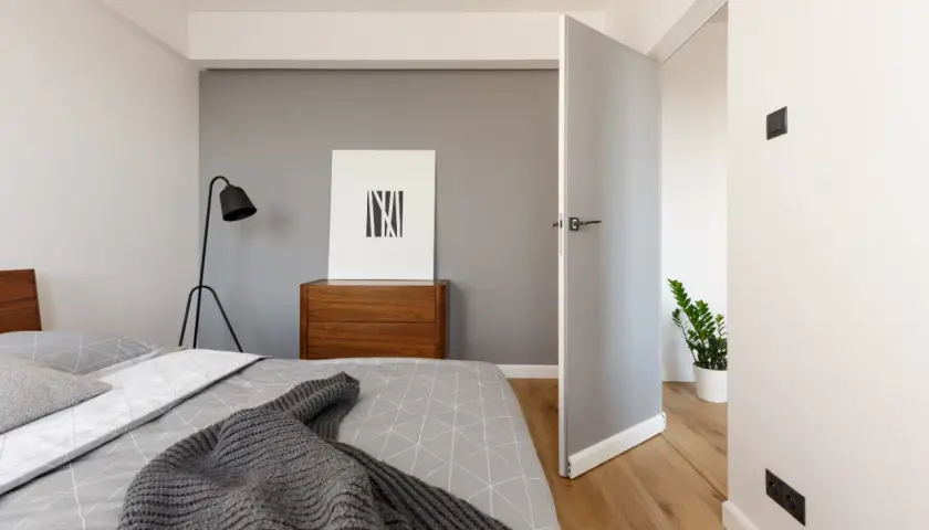 Nowoczesna sypialnia z łóżkiem, komodą i obrazem. Idealne miejsce na **najem krótkoterminowy**, oferujące komfort i styl.
