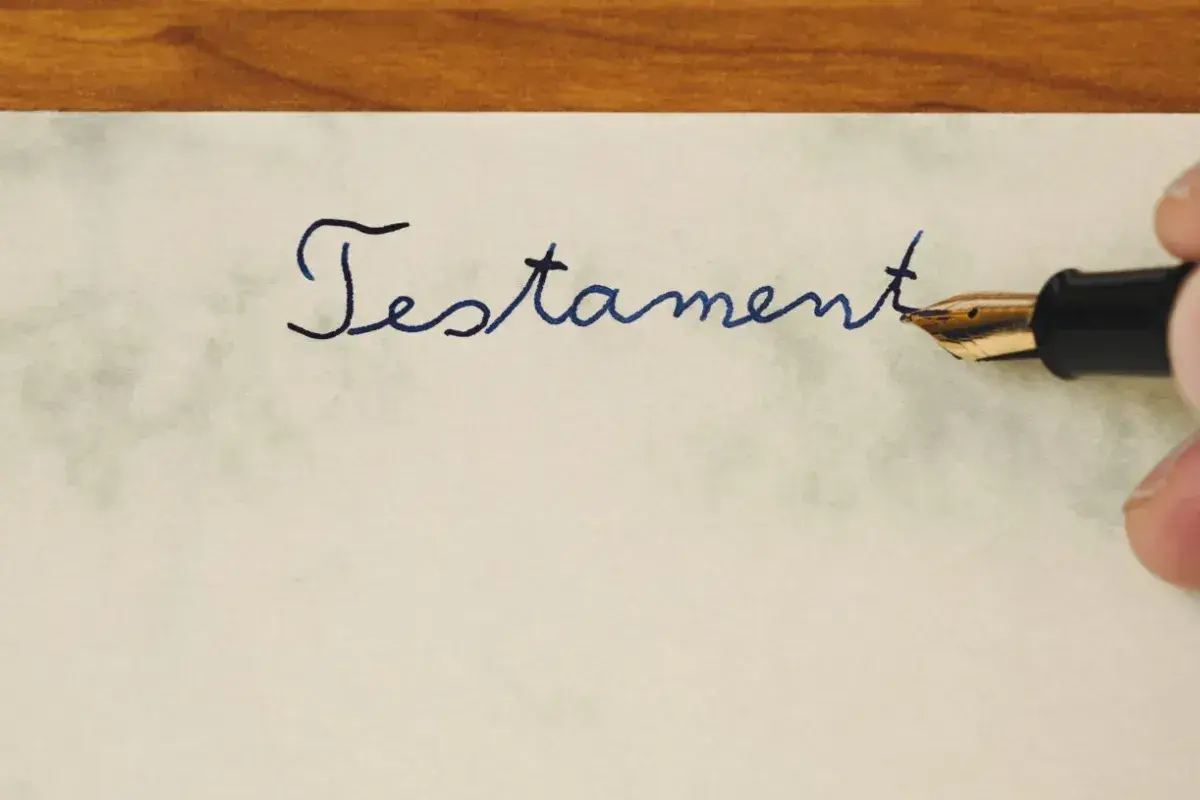 Pisanie atramentowym piórem słowa "Testament" na papierze. To ważny dokument, testament allograficzny, który wymaga precyzji.