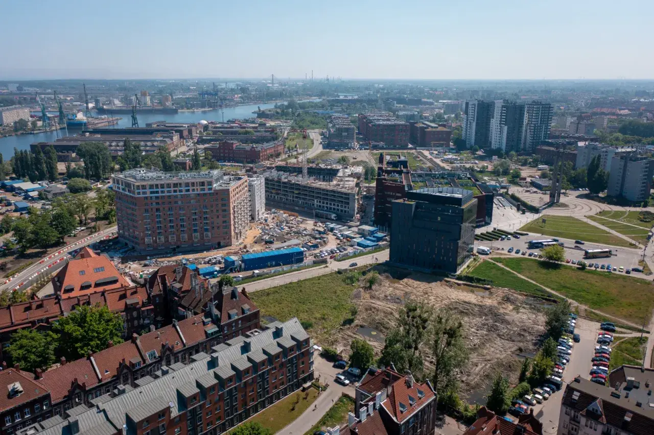 Widok z lotu ptaka na miasto z nowymi budynkami w budowie i portem w tle.
